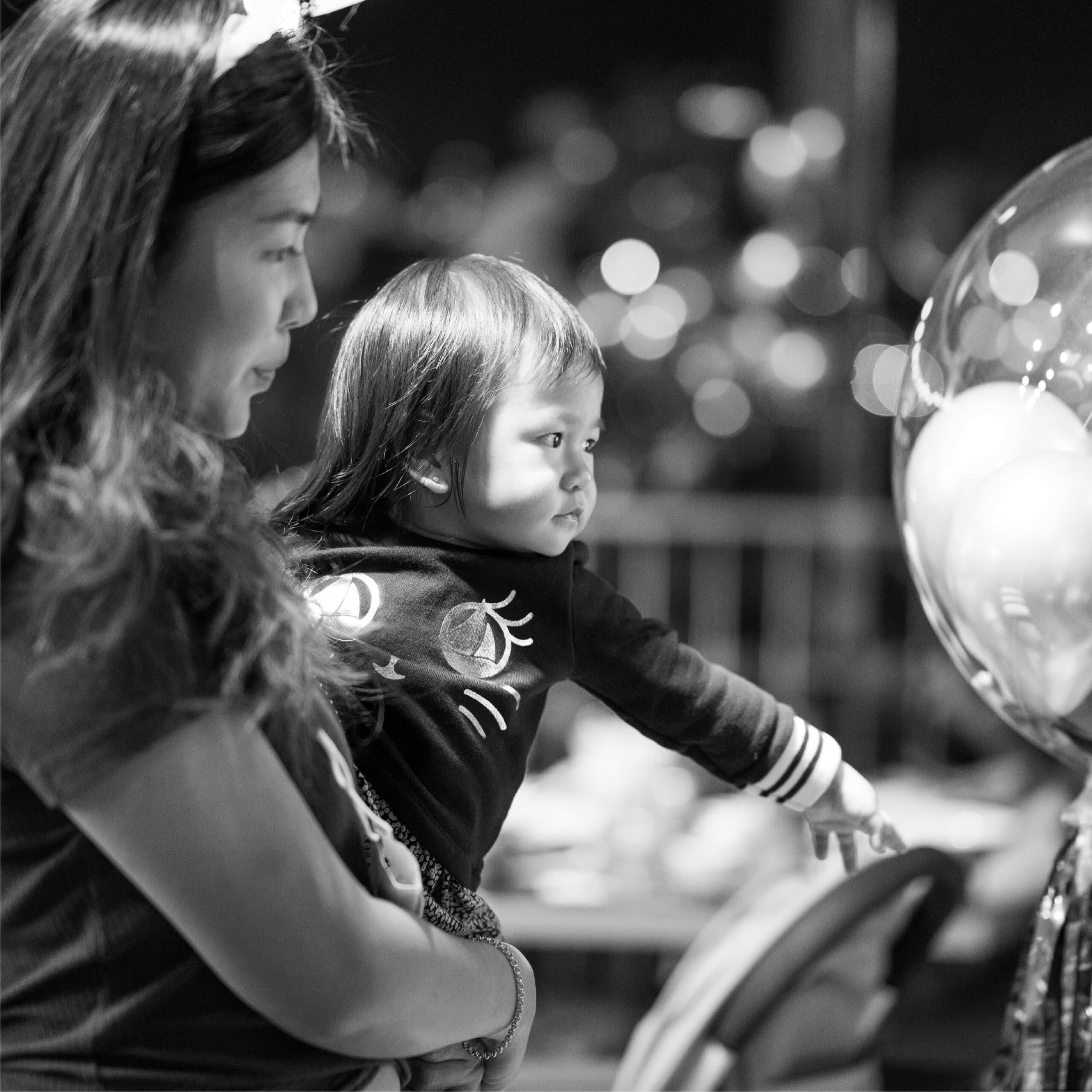 A parent holding a young child during a restaurant celebration.